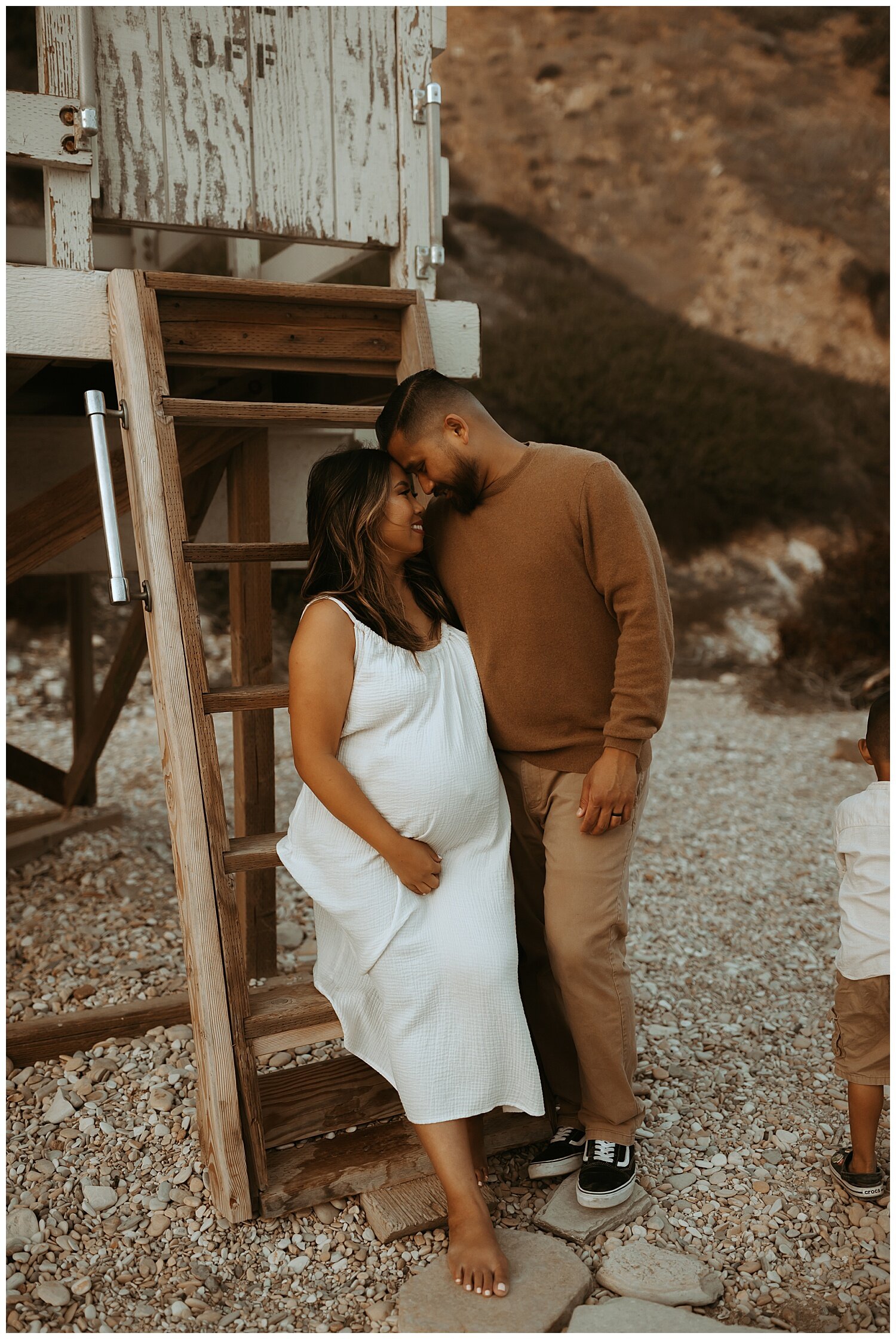 couple embracing during maternity photo session on Los Angeles beach